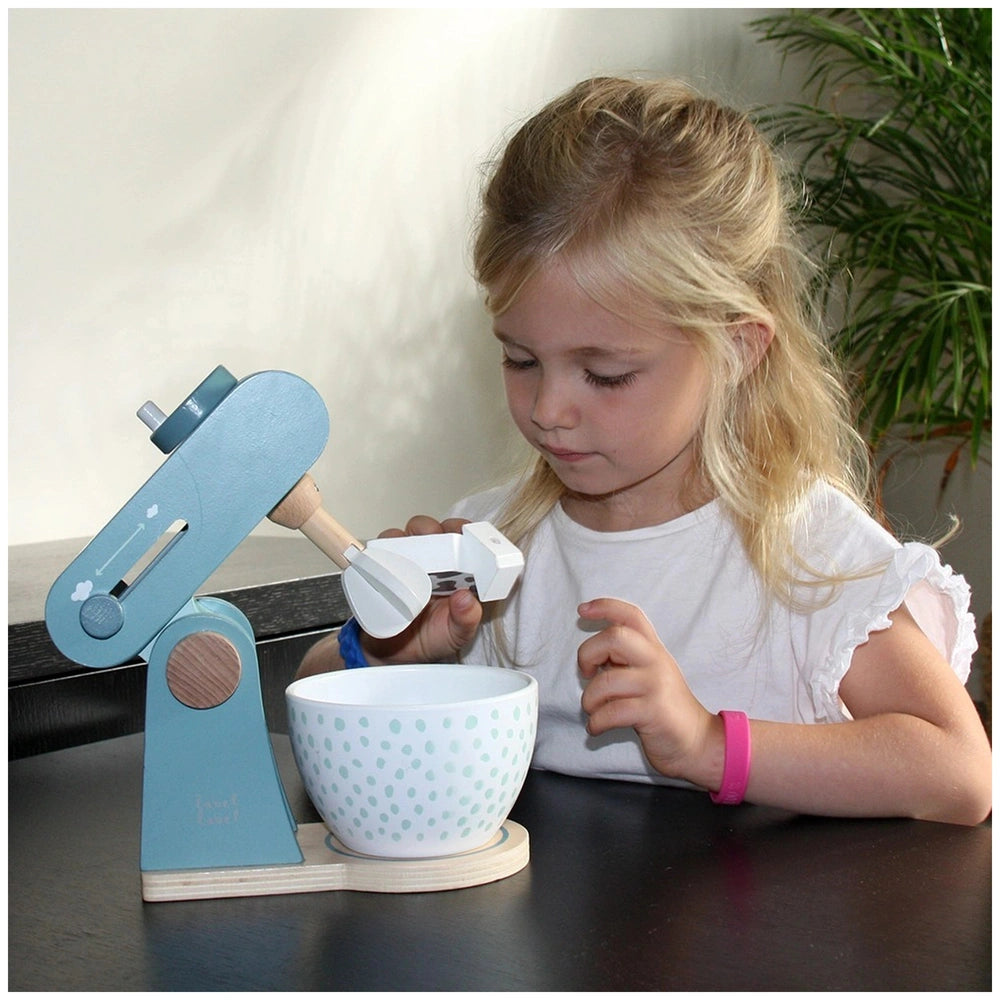 Label-Label Food Processor role-playing scene with a young girl, white bowl, blue measuring cup, and wooden tabletop.