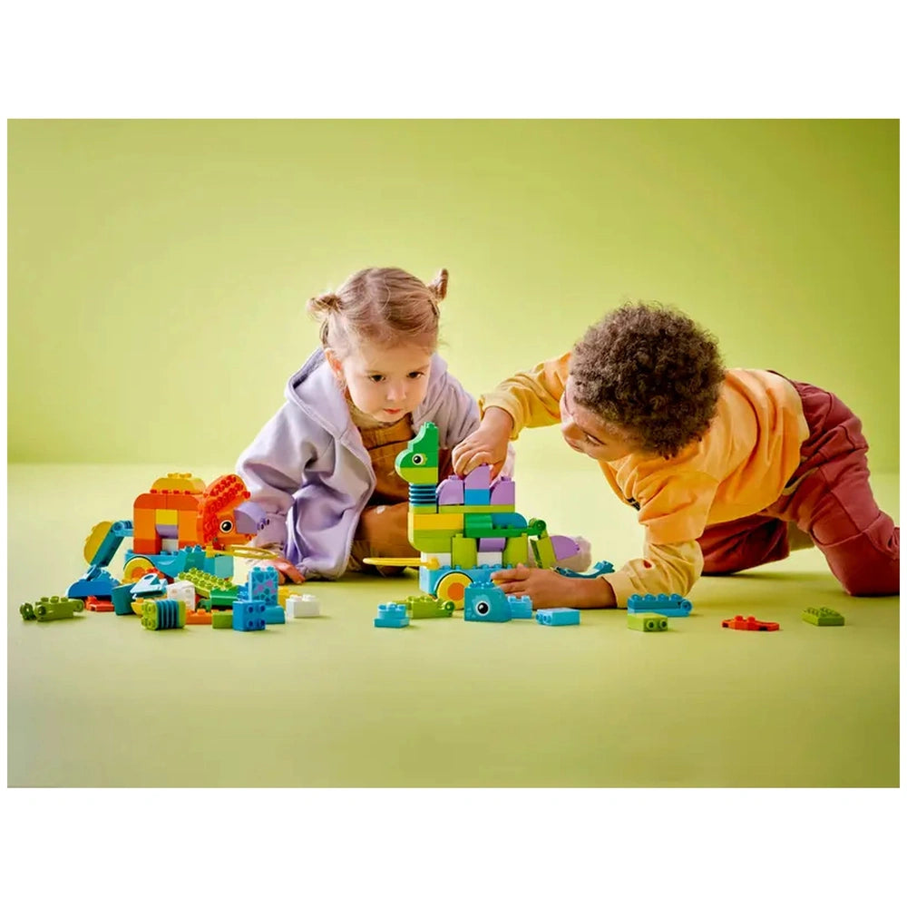 LEGO - 3in1-Dinosaurs-on-Wheels set with two children building colorful structures on a bright yellow floor.