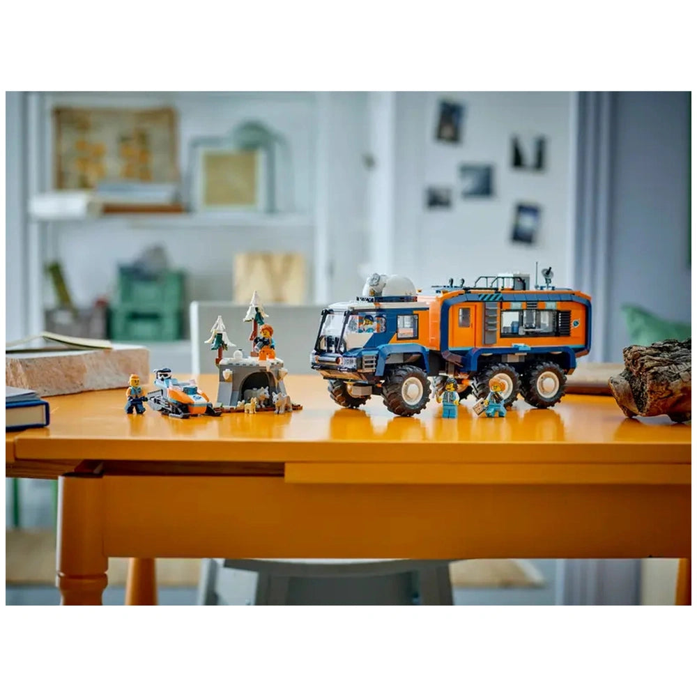 LEGO Arctic Explorer Science Lab Truck model in blue and orange on a wooden table with a toy person and car nearby.