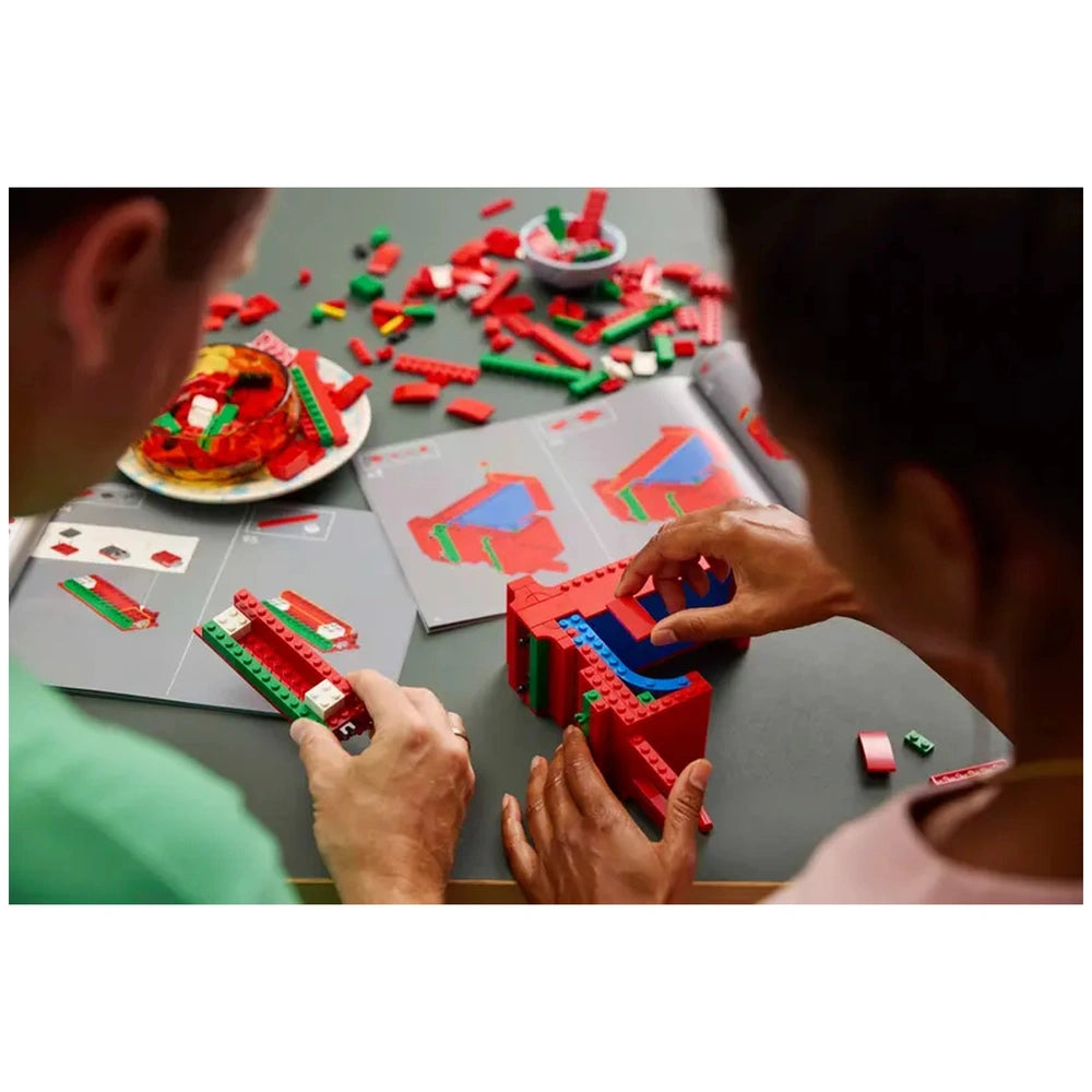 Lego - Art - LOVE construction set displayed on a light table with two individuals focused on assembling colorful bricks.
