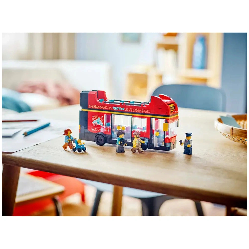 LEGO City Double-Decker Sightseeing Bus set on a wooden table, accompanied by four minifigures, including a driver and passengers. A soft, cozy background enhances the playful scene.