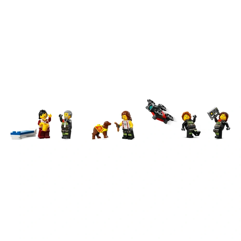 Five LEGO firefighter minifigures in action poses, accompanied by a brown dog wearing a cape. One figure holds a walkie-talkie, while another balances a toy drone. A blue and white structure appears in the scene, enhancing the playful firefighting theme.