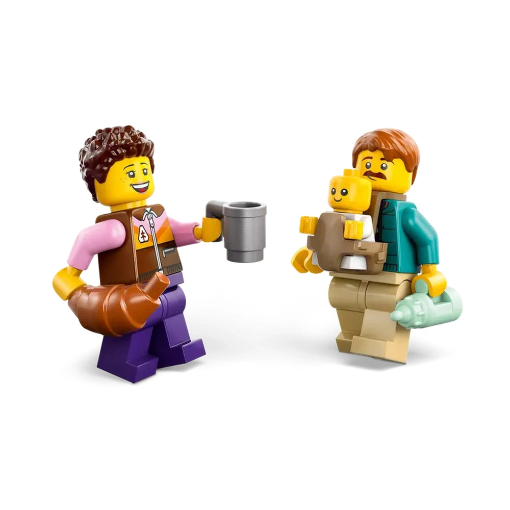 Two LEGO figures enjoy a cheerful moment outdoors; one holds a croissant and coffee, while the other carries a baby in a carrier, smiling.