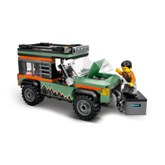 Lego City Off-Road Mountain Truck in green with orange accents, showing a child figure pretending to repair the engine with a tool.
