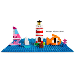 A vibrant blue LEGO® Classic baseplate features a red and white lighthouse, colorful sailboats, an orange fish, and coral.