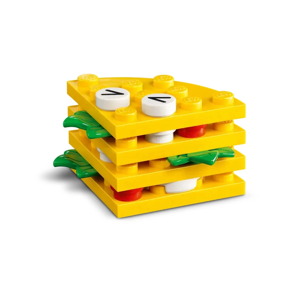 Colorful LEGO construction set depicting a stacked burger with yellow layers, green lettuce, and red toppings, perfect for creative play.
