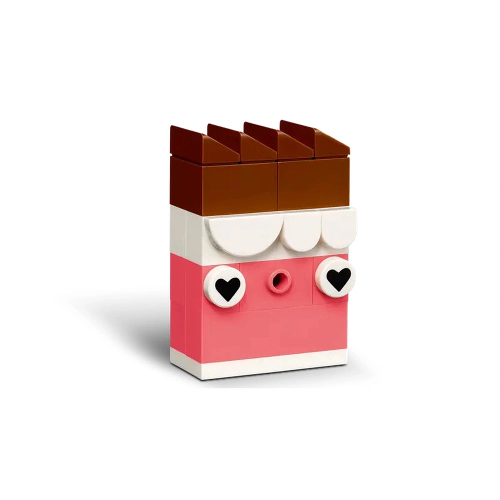 Colorful LEGO® construction set creates a whimsical cupcake character with brown chocolate topping, pink body, and heart-shaped eyes.