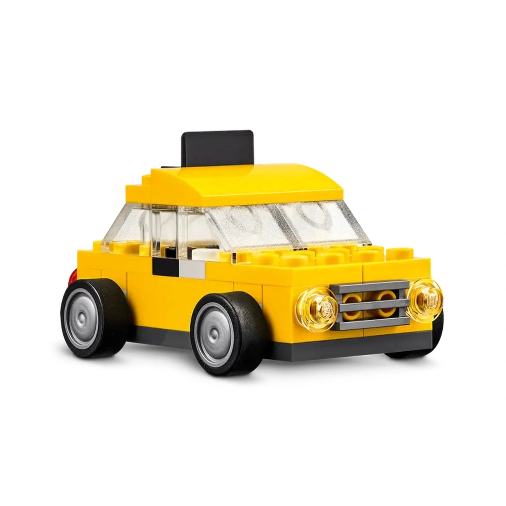 Yellow LEGO taxi toy with a black top, clear windows, and two round headlight pieces, showcasing colorful brick construction.