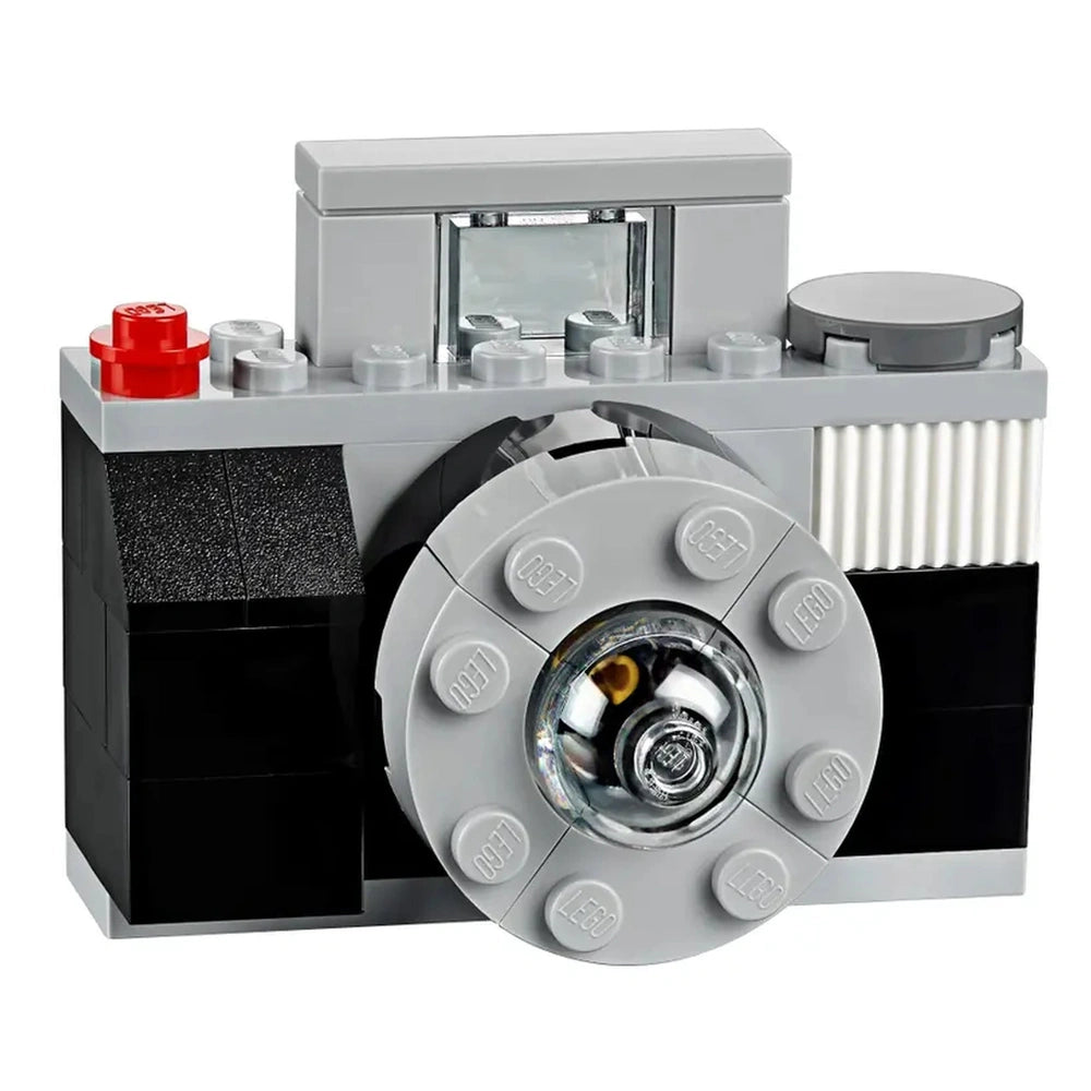 Classic LEGO camera model featuring grey and black bricks, a circular lens, and a red top button.