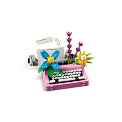 LEGO® Creator 3in1 pink typewriter surrounded by colorful flowers, featuring a moving keyboard and a sheet of paper.