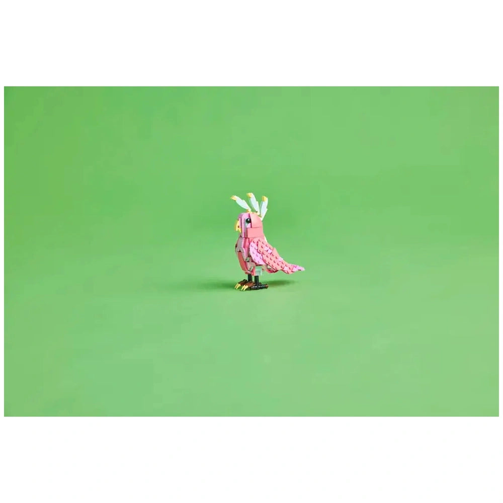 A vibrant pink LEGO® cockatoo with detailed wings and colorful head feathers stands against a bright green background.