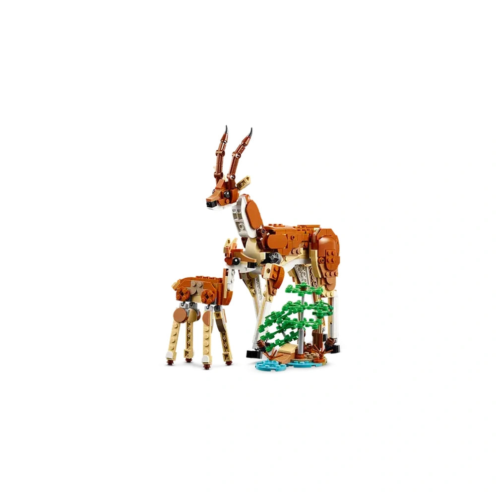 Two LEGO® models of safari animals: a large giraffe with articulated legs and a smaller giraffe, alongside a green tree and blue water.