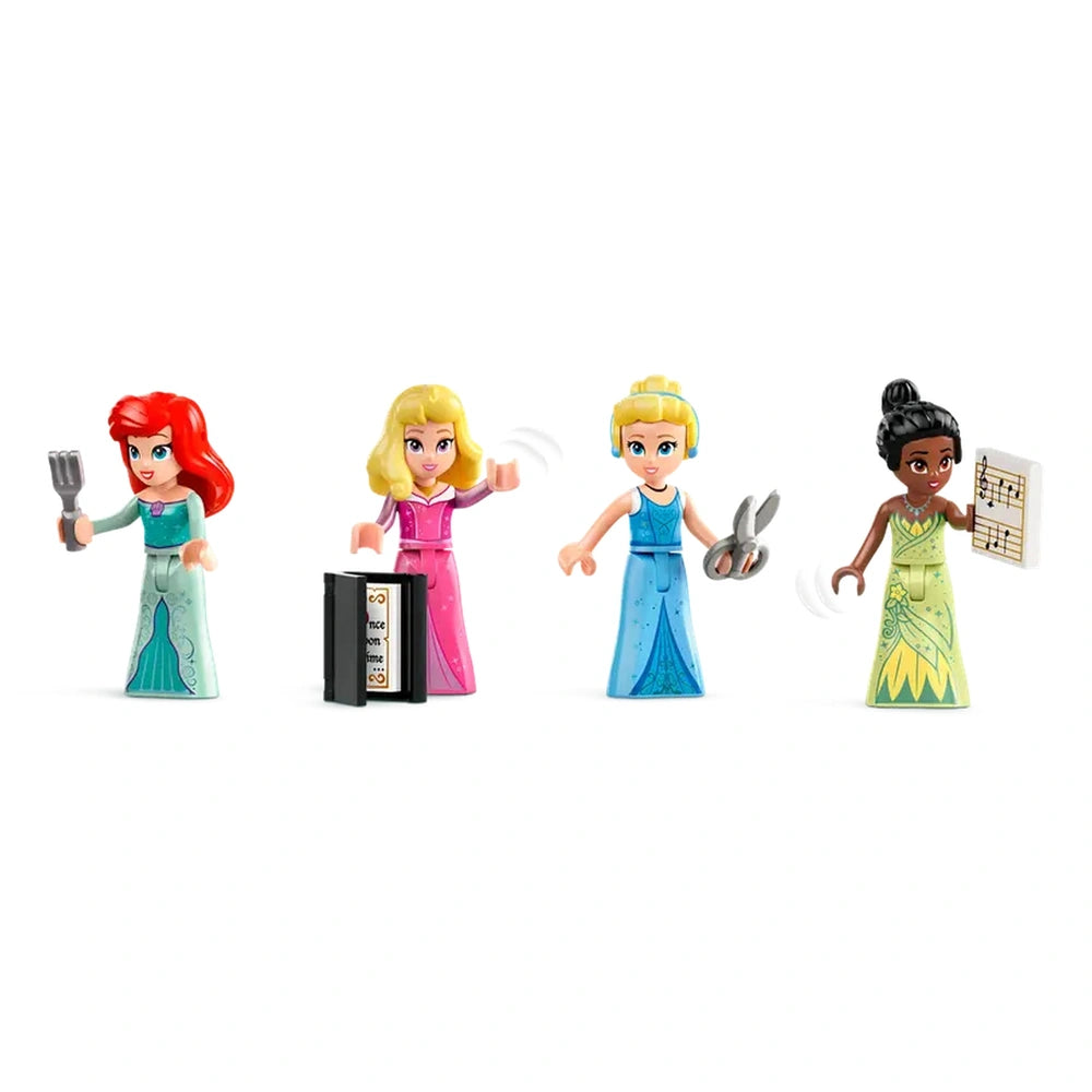 Four Lego Disney Princess figures standing in colorful gowns. From left to right: Ariel holding a fork, a blonde princess waving in pink, Cinderella with scissors, and Tiana with a music sheet, each showcasing distinct hairstyles and outfits.
