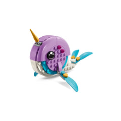 A colorful LEGO narwhal figure with a smiling face, featuring purple and turquoise body parts, a golden horn, and blue fins.