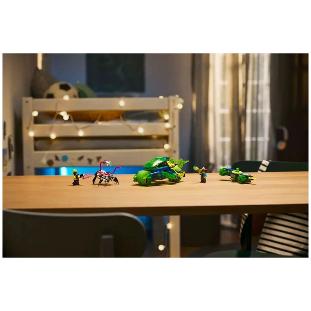Colorful LEGO® DREAMZzz™ Mateo and the Z-Blob Action Race Car set on a wooden table, featuring a green racing car, characters, and a spider figure. A cozy bedroom backdrop with fairy lights and a bunk bed is visible.