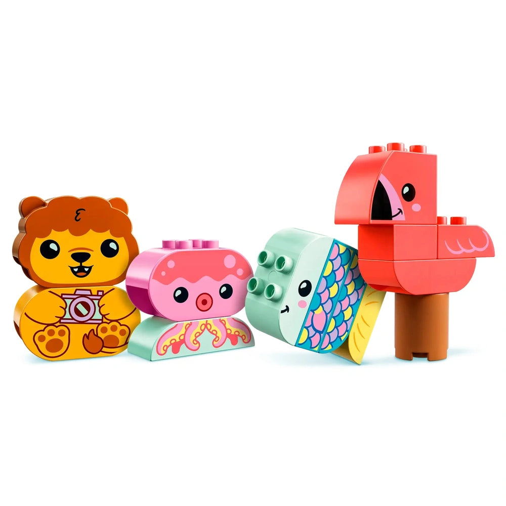 Four colorful LEGO DUPLO animal figures are arranged on a white background. A smiling lion with a camera, a cute pink octopus, a green fish with a patterned tail, and a vibrant red flamingo stand side by side, showcasing their playful designs.