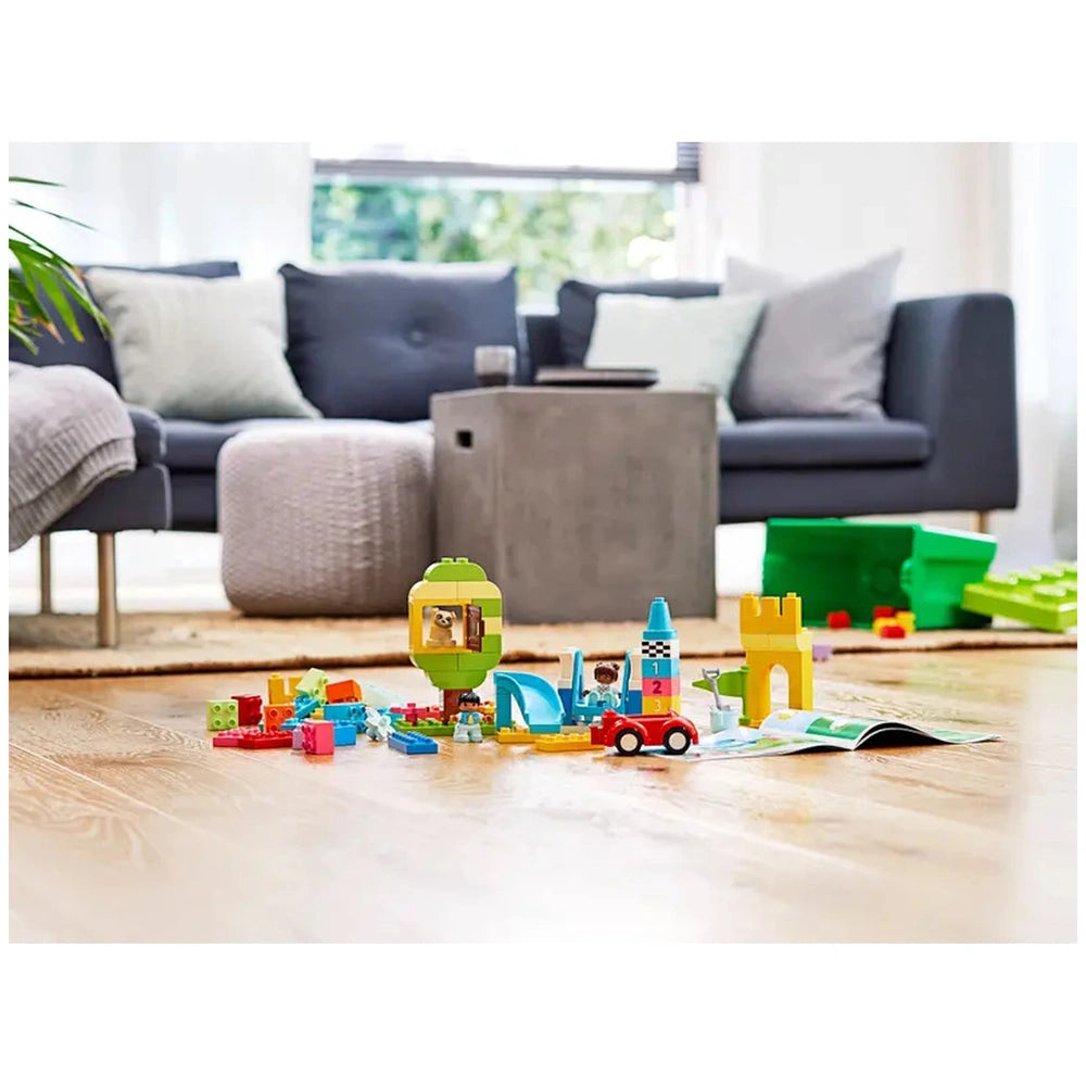 Colorful LEGO® DUPLO® bricks scattered on a wooden floor, featuring a castle, car, and a balloon with a smiling face, set in a cozy living room.