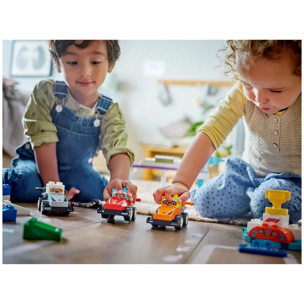 Two children play with colorful Lego Duplo race cars on a wooden floor, engaging in imaginative racing.