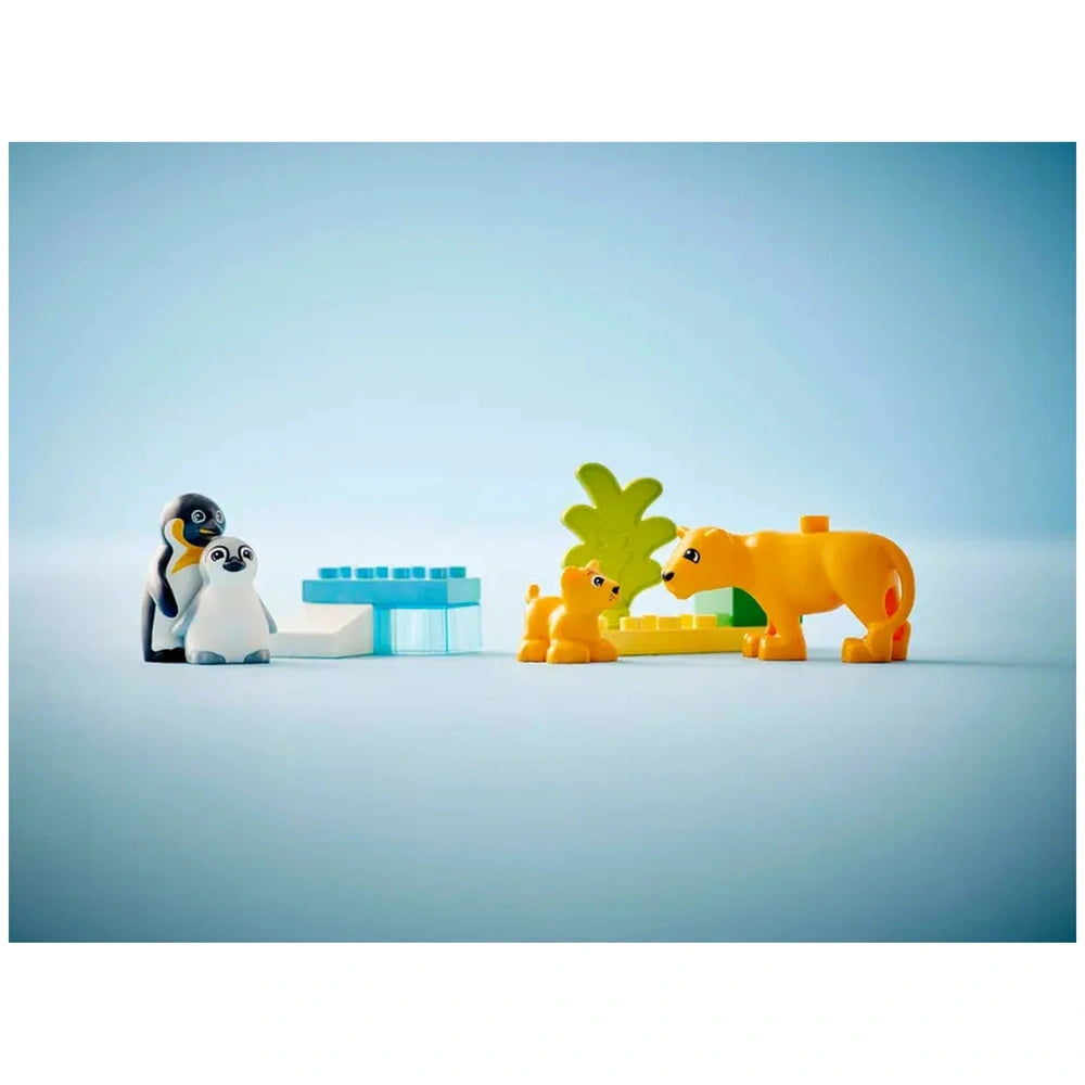 LEGO® DUPLO® set featuring two playful penguins beside a baby lion and a lioness, with colorful building blocks and a palm tree backdrop.