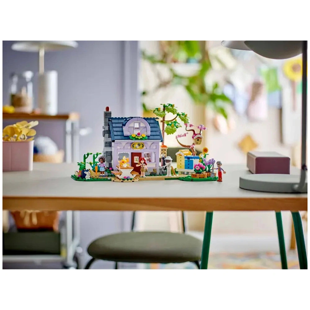 LEGO Friends Beekeepers' House and Flower Garden set, featuring a two-story house, vibrant garden, and four minidolls, displayed on a table.