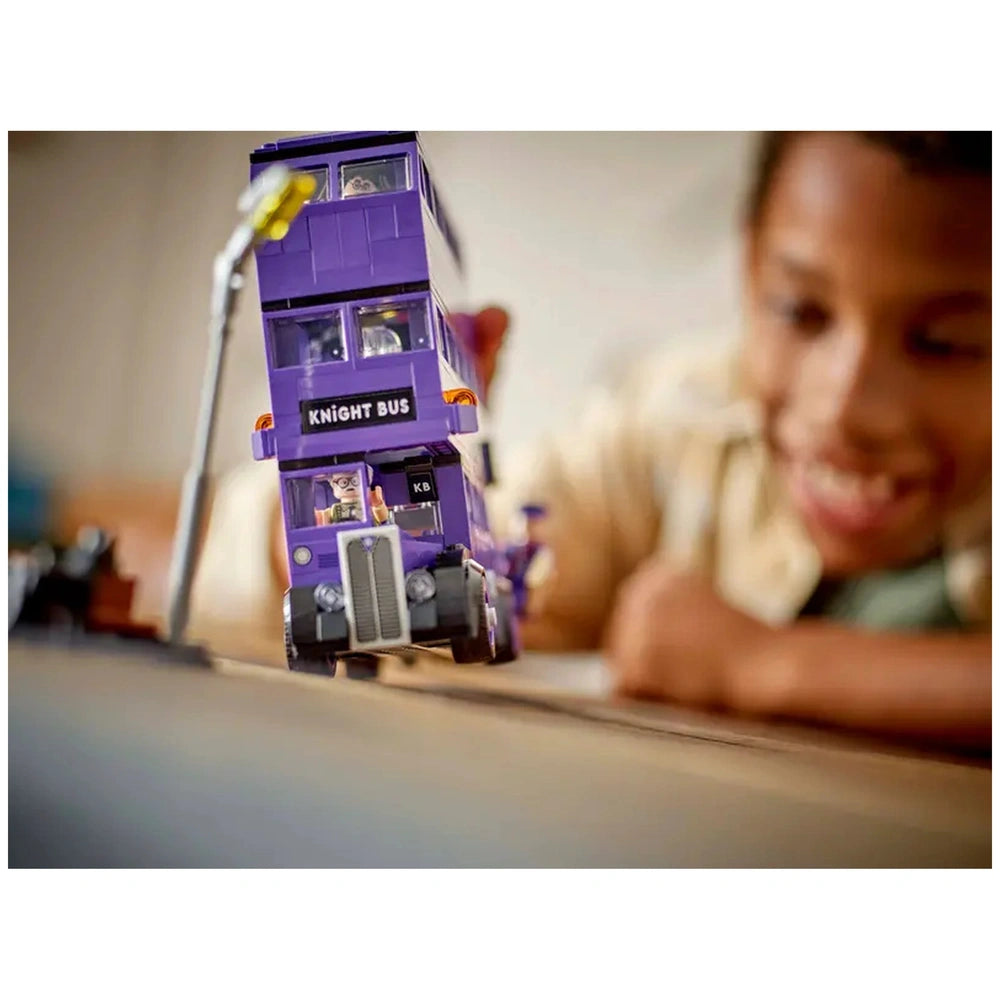 Knight Bus™ LEGO® set in vibrant purple, featuring intricate details and two mini-figures, as a child joyfully plays nearby.