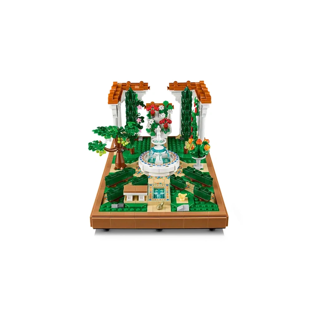 LEGO® Icons Fountain Garden construction set featuring a tiered fountain, vibrant flowers, and decorative pergolas in a lush green landscape.