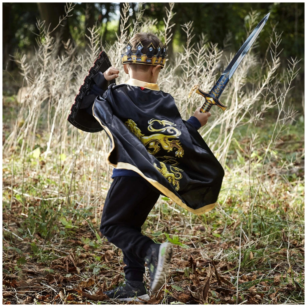 Young child in shiny black and gold costume holds Liontouch King Sword with blue handle, wearing a crown and headband.