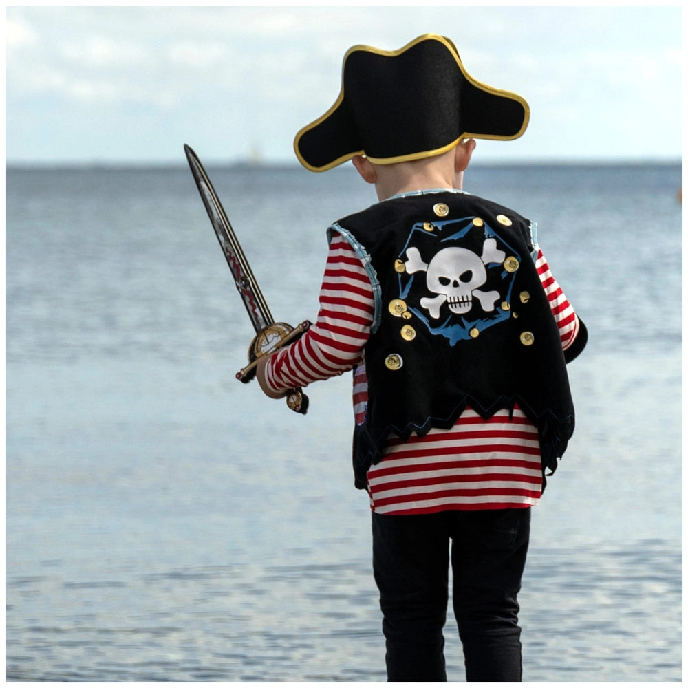 Child in pirate costume with a black vest and striped shirt, holding a silver-bladed sword near water.