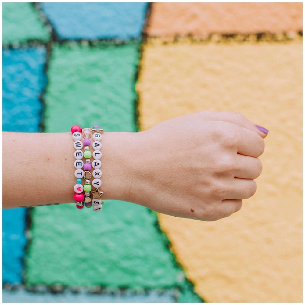 Block ‘N’ Rock Bracelet featuring colorful beads, a stretchy band, and a charm reading "SWEET" against a textured background.