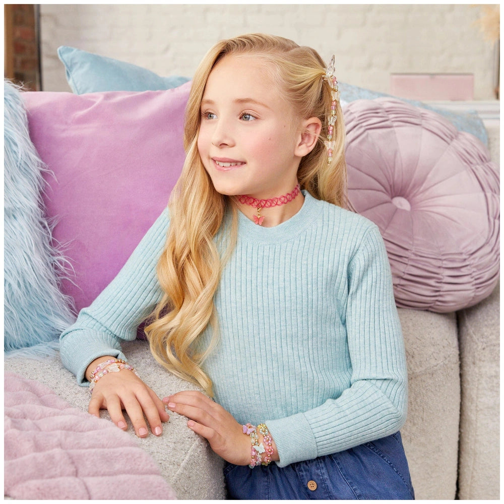 Butterfly Jewelry Set displayed on a young girl wearing a light blue sweater and red choker, sitting on a plush purple-blue c
