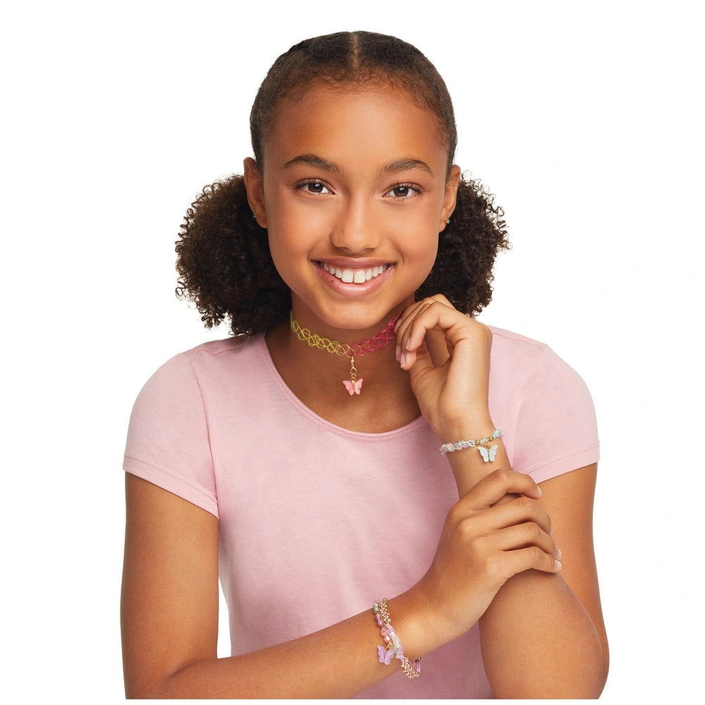 Butterfly jewelry set displayed on a child with curly brown hair, wearing a pink t-shirt and a pink heart pendant necklace.