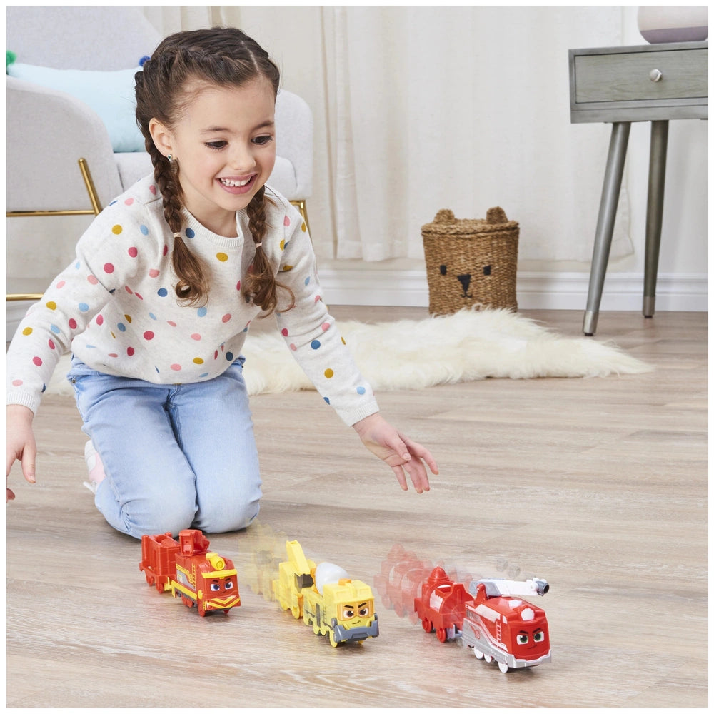 A young girl with braids plays happily on the floor with colorful toy trains in a bright, cozy room.