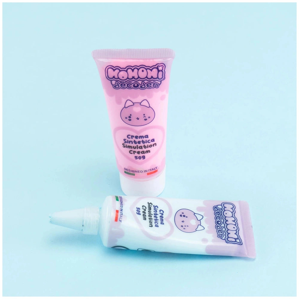 Momomi Decoden Kawaii Artist includes pink and white cream and solution tubes with glossy packaging on a light blue backgroun