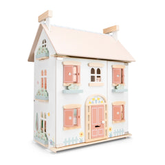 New Classic Toys dollhouse features a white exterior, pink door, wooden accents, and transparent windows, showcasing detailed