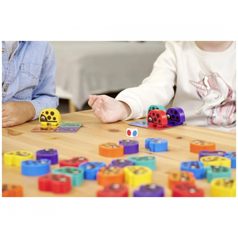 Noris - 3 Colorful Bug Games showing children playing with vibrant game pieces on a wooden surface in a casual setting.
