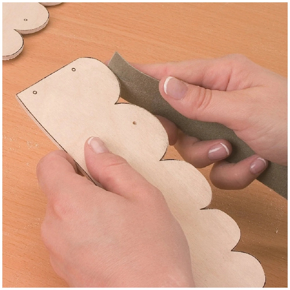 Sanding a scalloped wooden piece from the Prebaro Fretwork Carpenter's Case on a wooden surface.