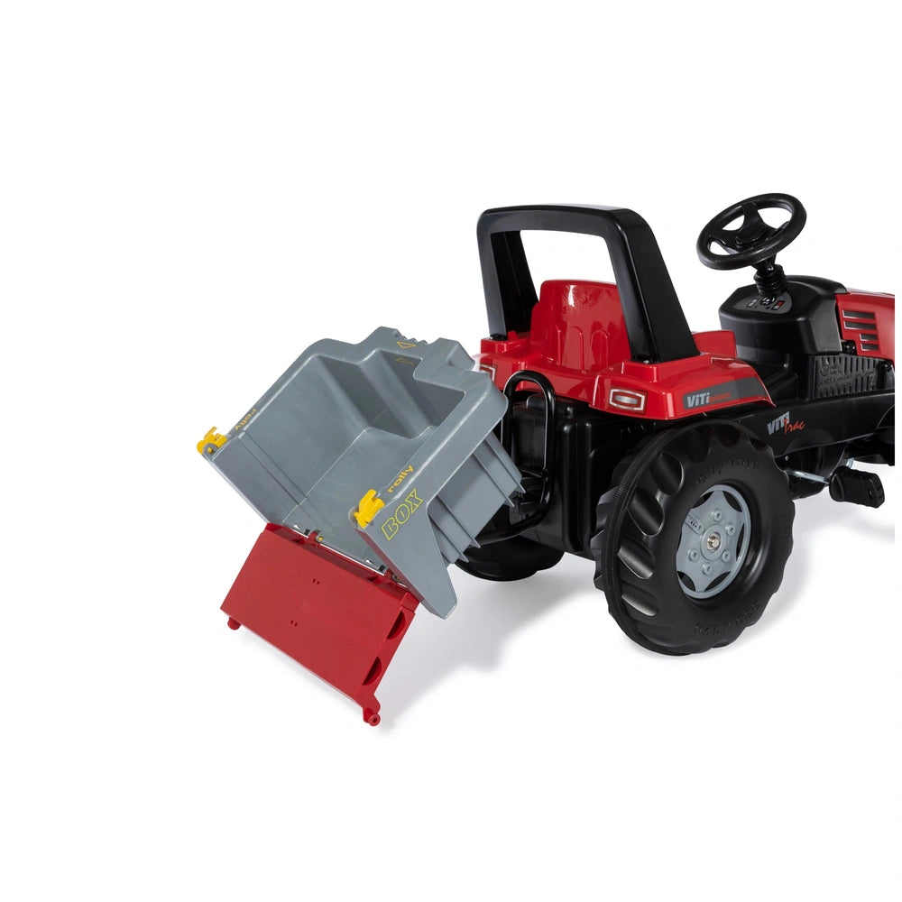 Rolly Toys John Deere toy tractor in red with black wheels, positioned on a matching red plastic surface.