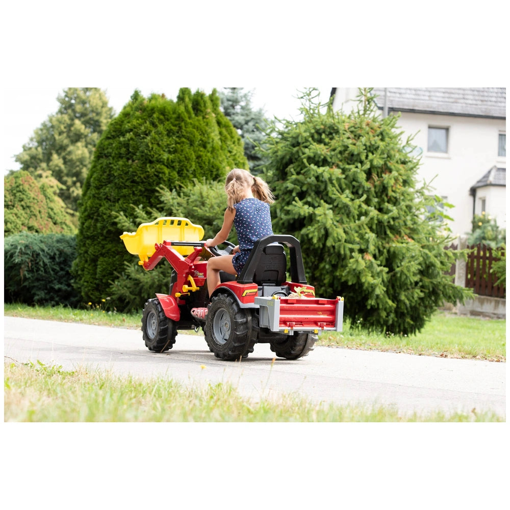 A young girl in a blue top rides a red and yellow four-wheeler with a front basket on a paved road.