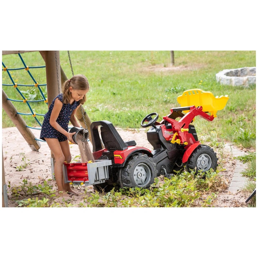 Rollybox John Deere four-wheeler in red and black with a yellow seat, next to a girl in a sleeveless dress outdoors.