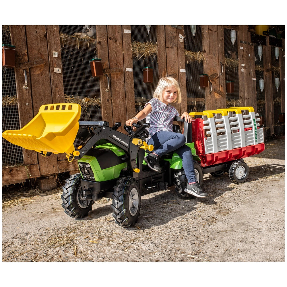 Rollyhay Wagon Pottinger Trailer ATV with a young girl in a light top, surrounded by hay bales and a wooden structure.