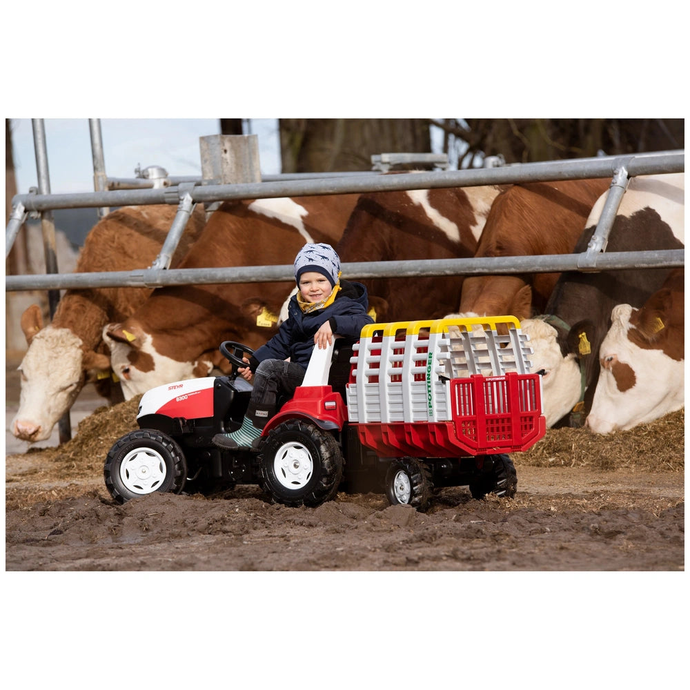 Rollyhay Wagon Pottinger Trailer on dirt, with a child in a blue jacket and gray hat riding a red four-wheeler near an open m