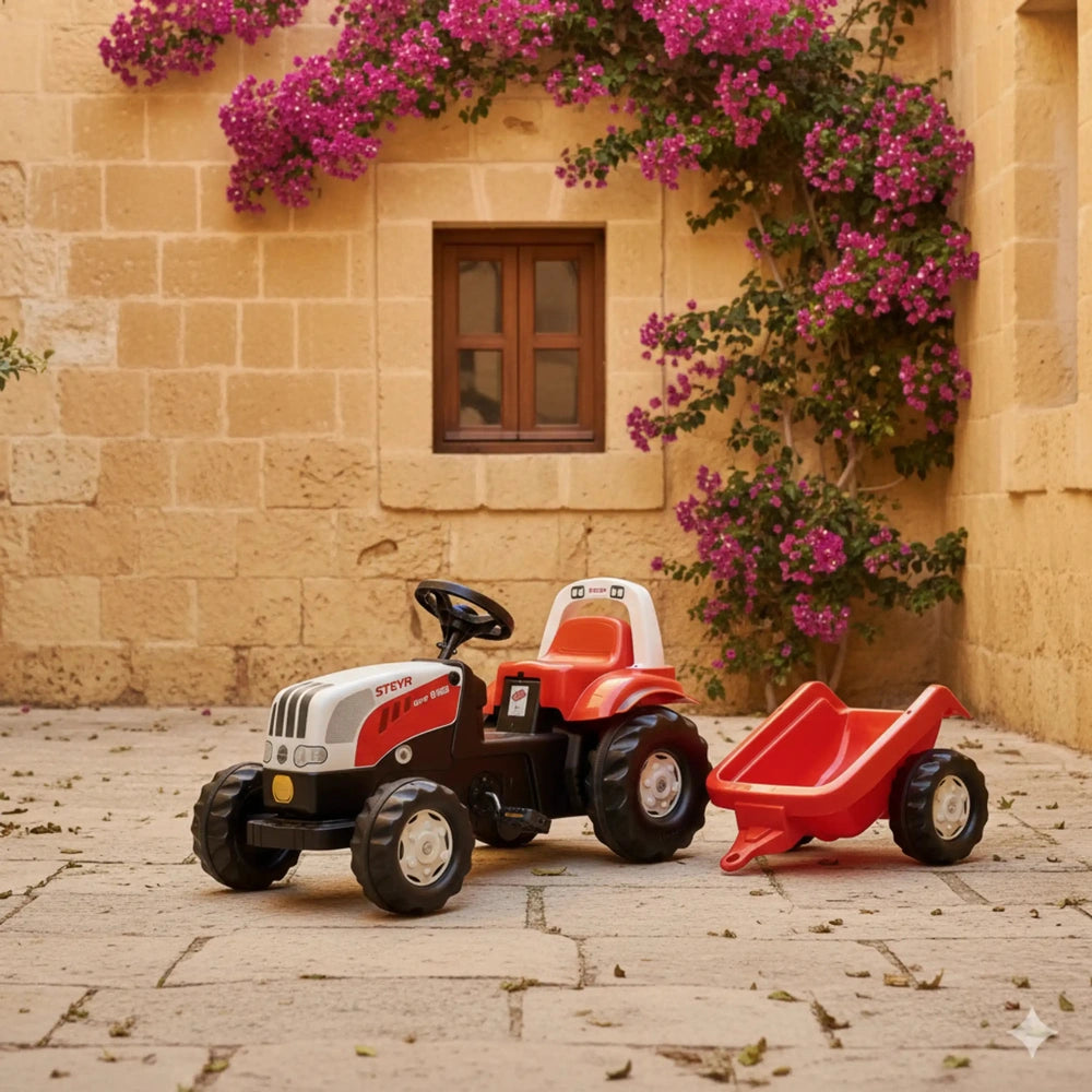 Rolly Toys Rollykid Steyr 6165 CVT tractor in red and white with a matching red wagon near a beige stone wall and pink flower