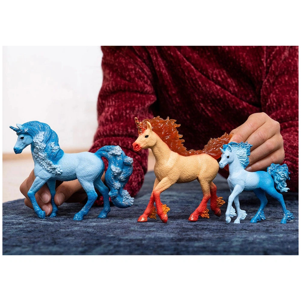 Bayala Elementa Water Unicorn figurine held by a hand, showcasing glossy blue, red, and white details on dark blue fabric.