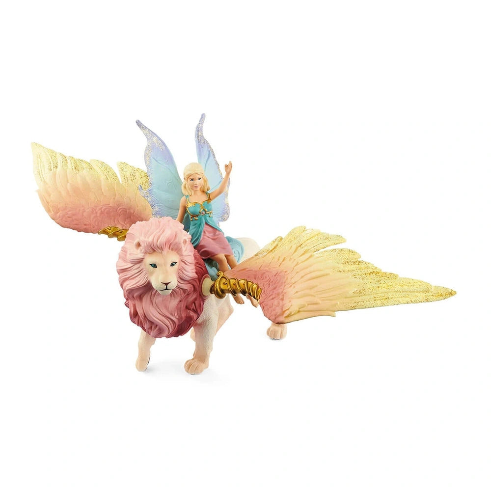 Schleich Bayala fairy in flight on a winged lion, featuring a pink mane, blue wings, and golden accessories.