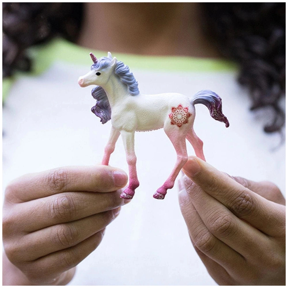 Mandala Unicorn Foal figurine with white body, blue mane, pink hooves, and red marking on a matte plastic surface.