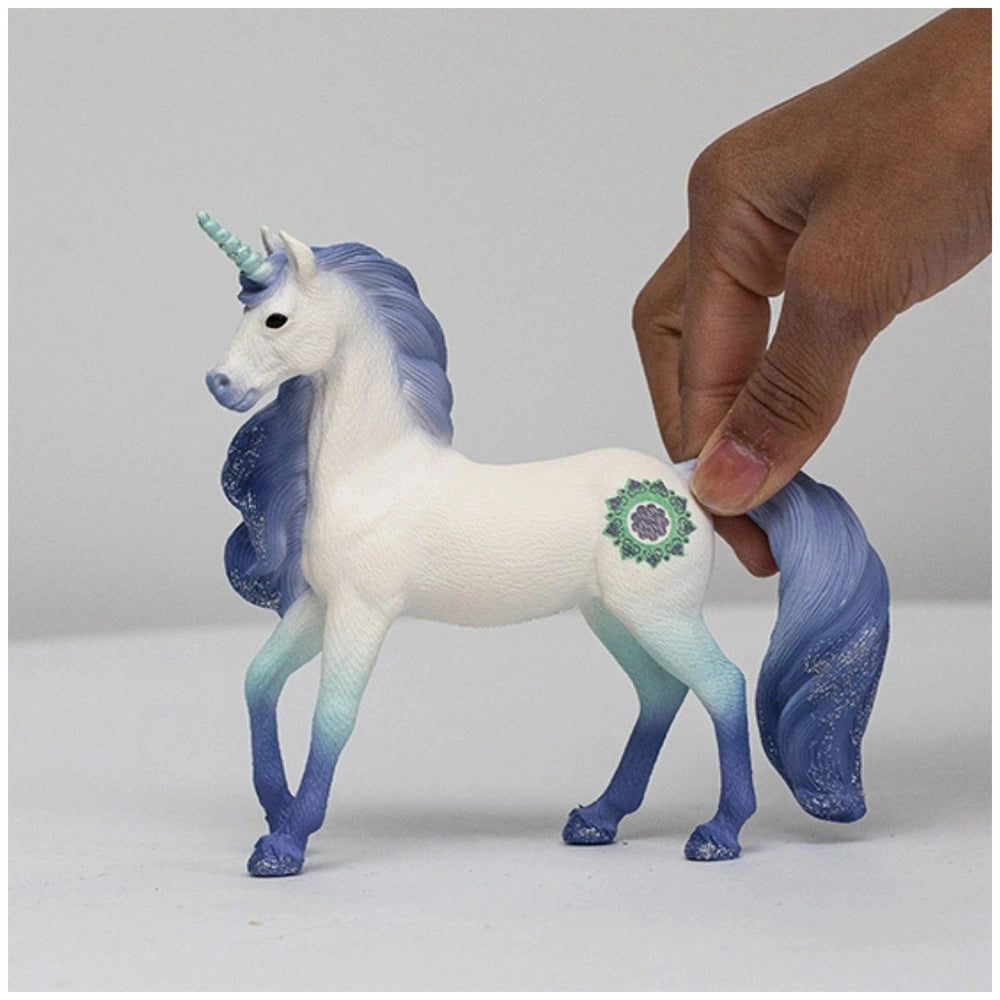 Mandala Unicorn Stallion figurine features a white body, blue mane and tail, and a green and purple design, held in a hand.
