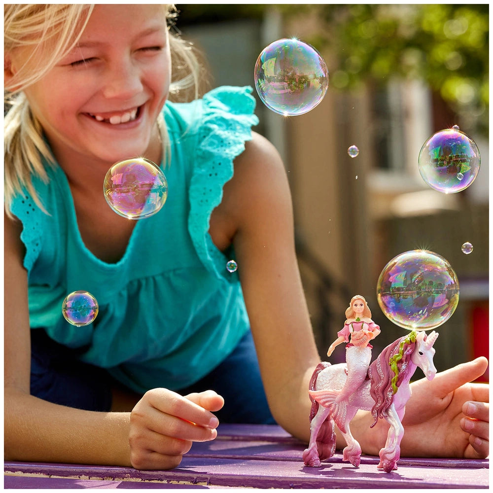 Schleich Bayala Mermaid Feya figure with girl at a purple table, smiling and playing with a bubble wand.