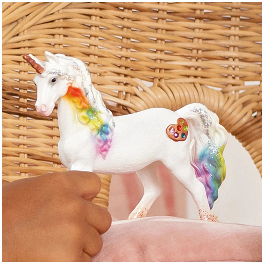 Rainbow Love Unicorn Mare figurine with multicolored mane, white body, and heart decoration on a textured brown basket.