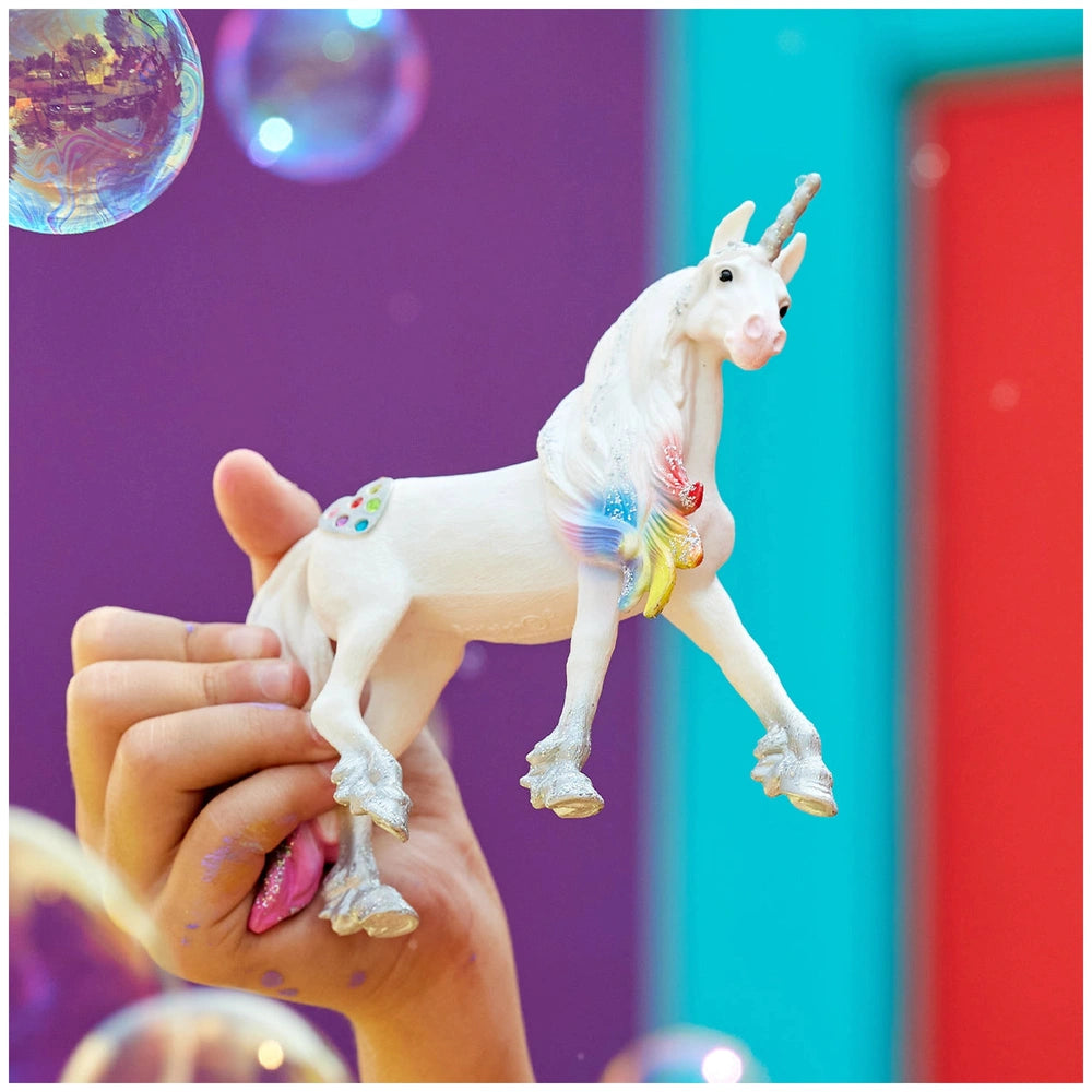 White glossy plastic unicorn figurine on a gradient purple and blue background, representing Schleich's Rainbow Love Unicorn 