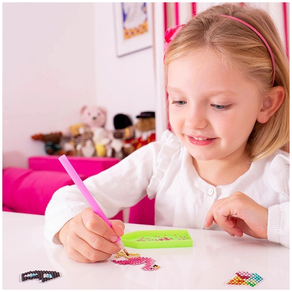 Sentosphere - Diamond Stickers are being used by a smiling girl in a white top and pink headband, drawing with a pink crayon.
